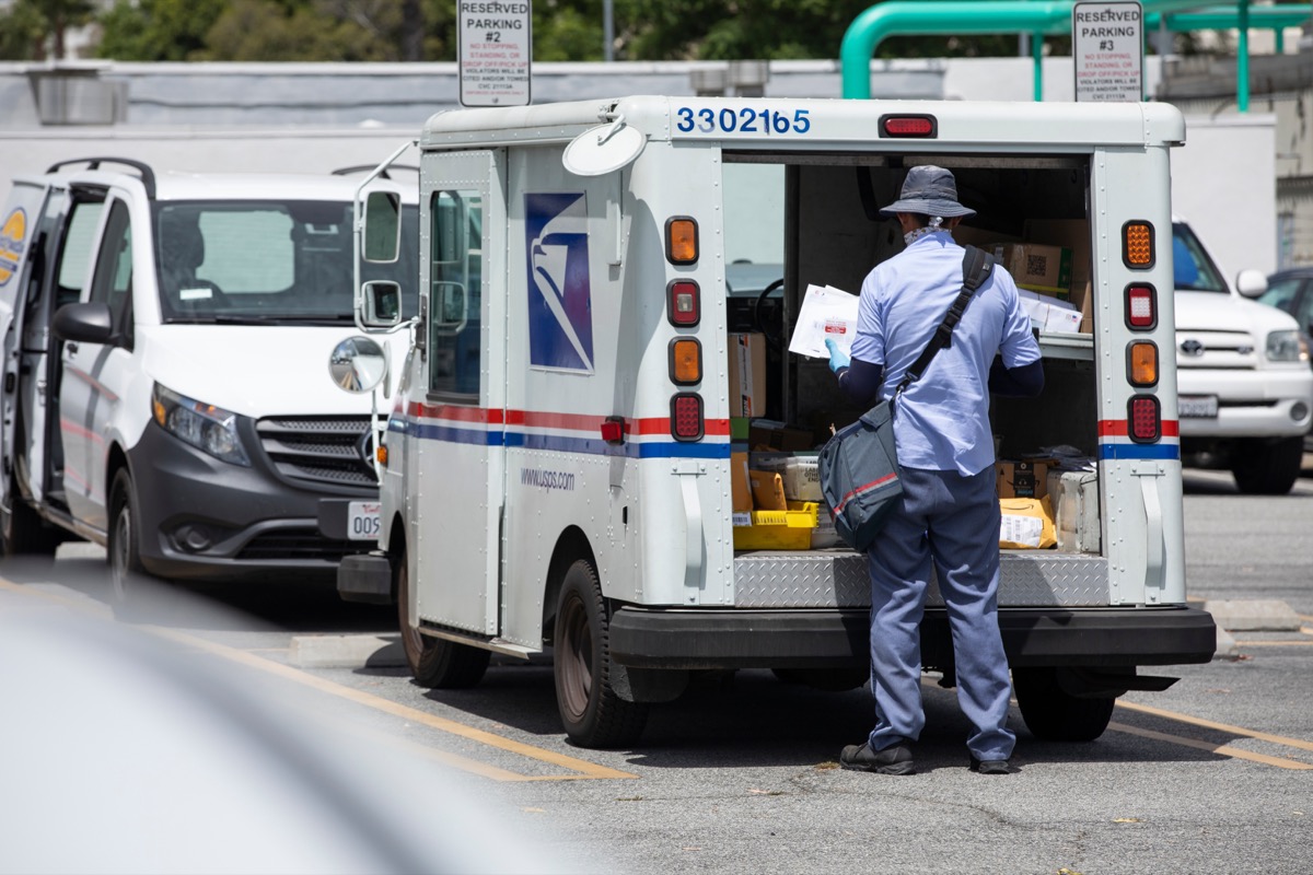 A USPS (United States Parcel Service) mail truck and mail carrier make deliveries.